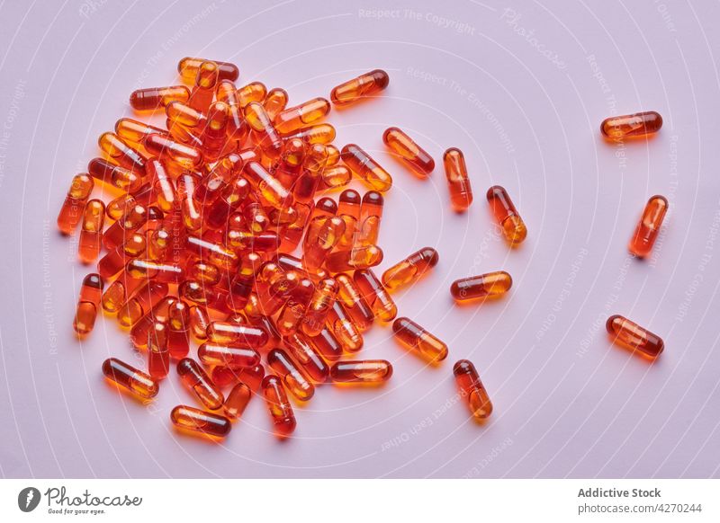 Orangefarbene Pillen auf rosa Oberfläche verstreut Tablette Medikament Kapsel Kur Streuung Zusammensetzung orange Abhilfe Vitamin Leckerbissen Apotheke