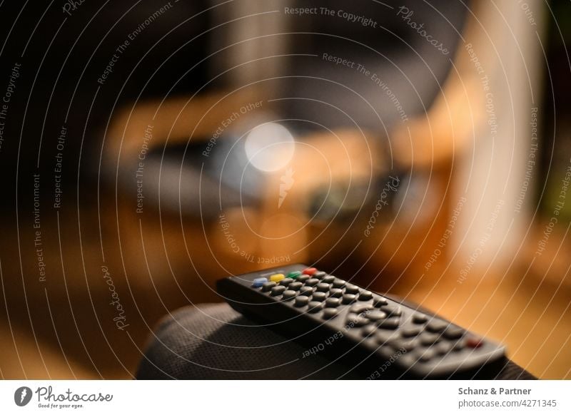 Fernbedienung auf der Armlehne der Couch Sessel Fernsehen abendunterhaltung Netflix Streaming umschalten zuhause Couch-Potato Sofa Wohnzimmer Innenaufnahme