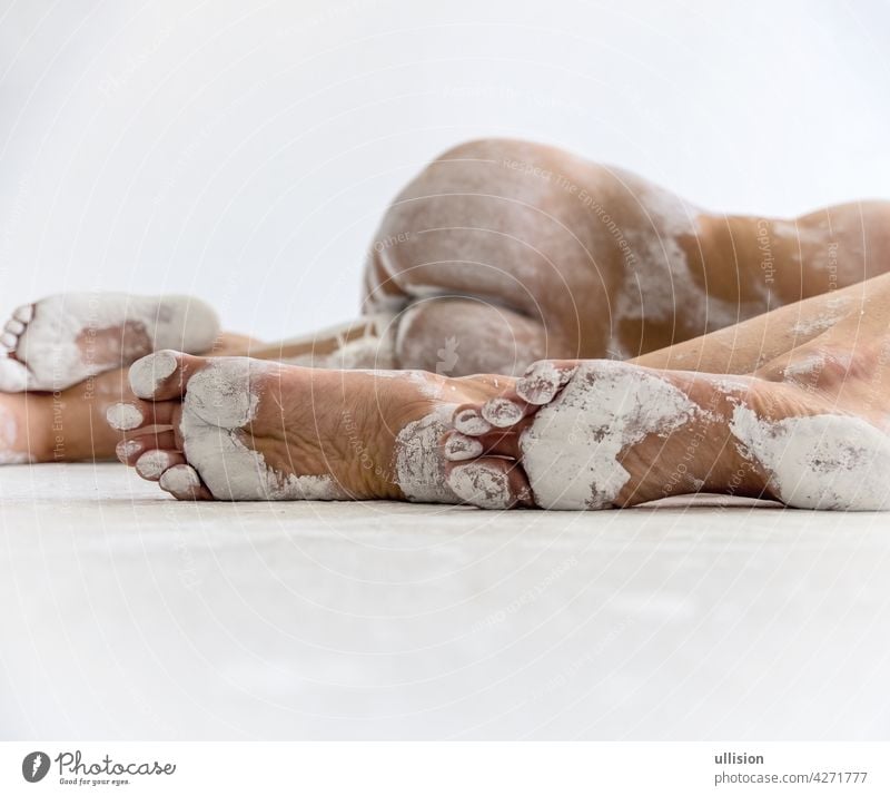 drei Füße von zwei jungen abstrakt gemalten sexy Frauen in weißer Farbe, die auf dem Boden des Künstlerateliers liegen, Kopierraum Fuß Mädchen attraktiv