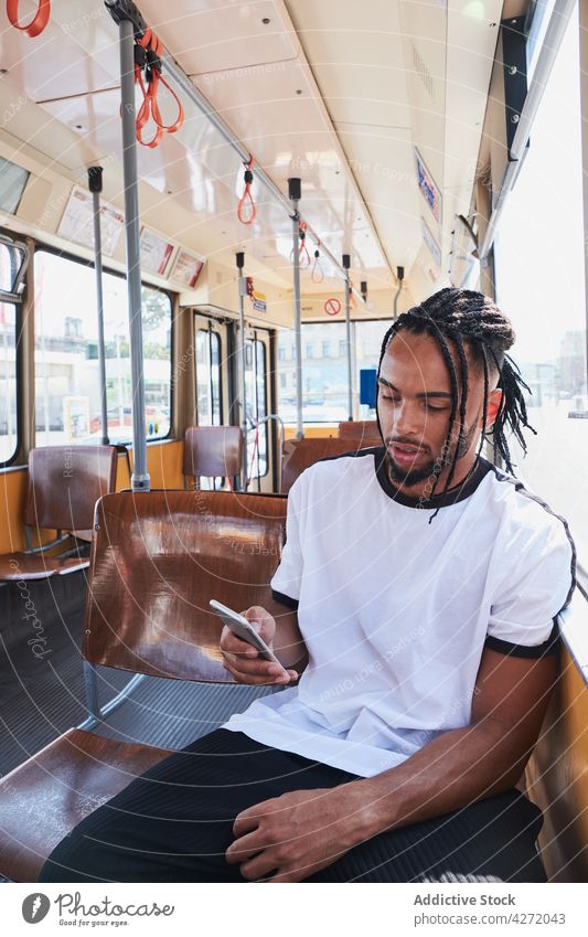 Schwarzer Mann sitzt im Bus und benutzt Smartphone Zug Passagier Sitz Verkehr allein Großstadt positiv männlich jung schwarz Afroamerikaner Wiena-Bahn ethnisch