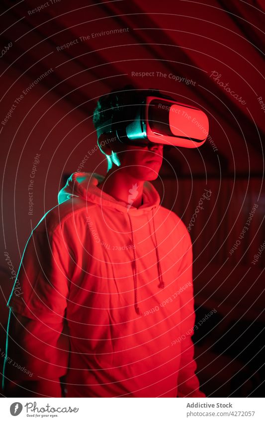 Seriöser Typ mit VR-Brille in neonfarbenem Raum Mann modern Headset Atelier neonfarbig ernst Virtuelle Realität rot männlich Licht Schutzbrille Gerät Apparatur