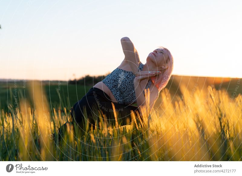 Frau Durchführung Crescent Lunge mit Prayer Hands Pose im Feld halbmondförmiger Ausfallschritt Gebetshände Seitenknick Yoga Wellness Energie Vitalität