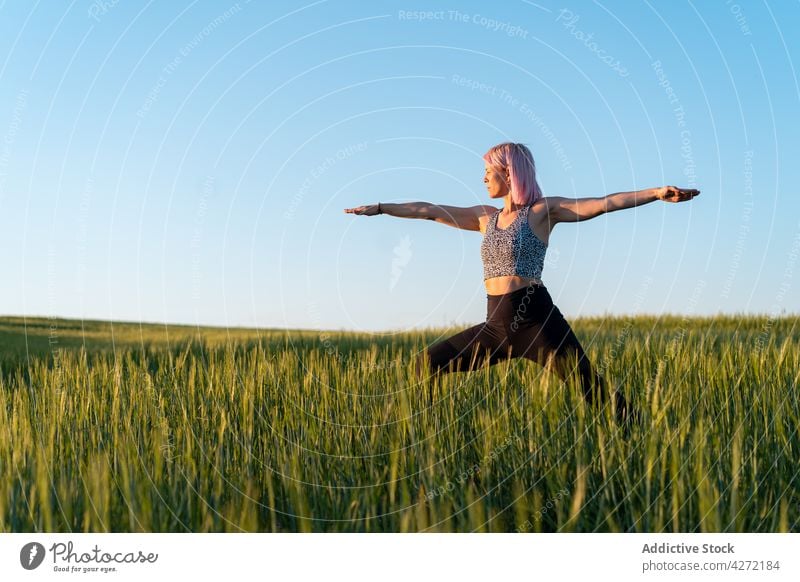 Frau stehend in Warrior Pose in der Landschaft Feld Krieger-Pose Yoga Gesunder Lebensstil Wohlbefinden Vitalität Energie ausdehnen üben Wellness Wiese Gras