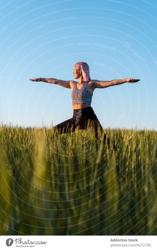 Frau stehend in Warrior Pose in der Landschaft Feld Krieger-Pose Yoga Gesunder Lebensstil Wohlbefinden Vitalität Energie ausdehnen üben Wellness Wiese Gras
