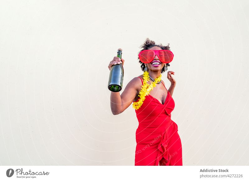 Glückliche schwarze Frau in stilvoller Kleidung mit einer Flasche Champagner feiern Party Stil Mode trinken Alkohol Brille stylisch rot Bekleidung Ohrringe
