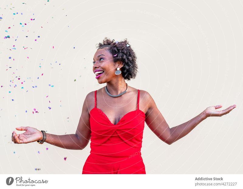 Glückliche afroamerikanische Frau steht während einer Feier unter Konfetti fallen Feiertag feiern aufgeregt Lachen erstaunt Überraschung Spaß expressiv positiv