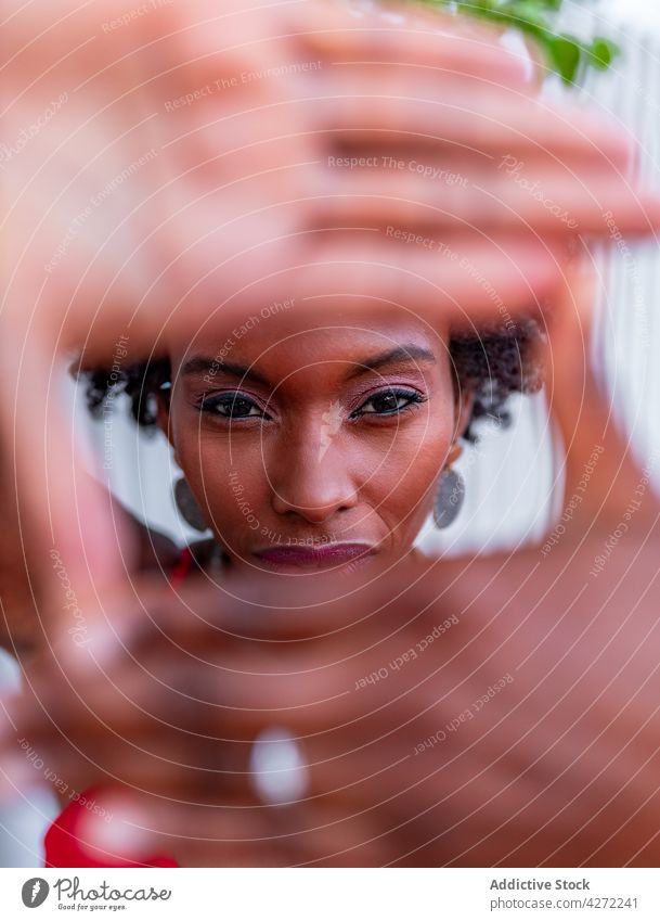 Schwarze Frau zeigt Rahmengesten bei Tageslicht Foto Perspektive feminin herzlich Starrer Blick sanft gestikulieren Porträt Stil freundlich rot Farbe Fotografie