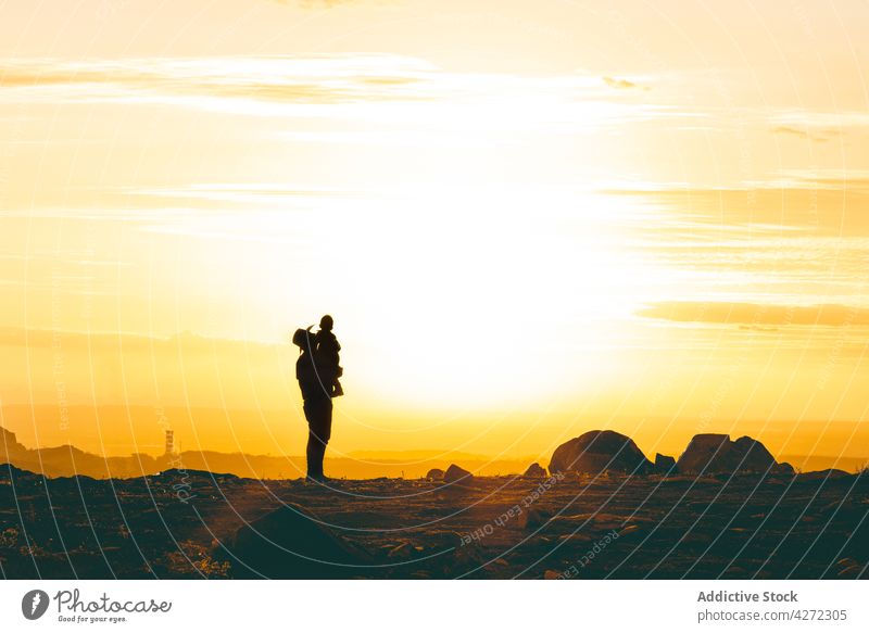 Unbekannter Vater hält Sohn in der Luft in der Wüste bei Sonnenuntergang Mann Kind wüst felsig Tal Zusammensein männlich Junge Halt hell Landschaft Vaterschaft