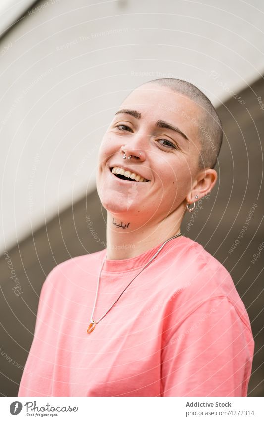 Androgyne Person in der Nähe eines gemauerten Gebäudes auf der Straße androgyn Transgender Lächeln akzeptieren heiter Identität Glück nicht binär queer