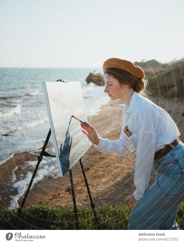 Künstlerin am Ufer bei Sand und Meer beim Malen Frau Farbe zeichnen Hobby MEER Kunst Leinwand jung Staffelei Baskenmütze Augen geschlossen kreativ Kunstwerk