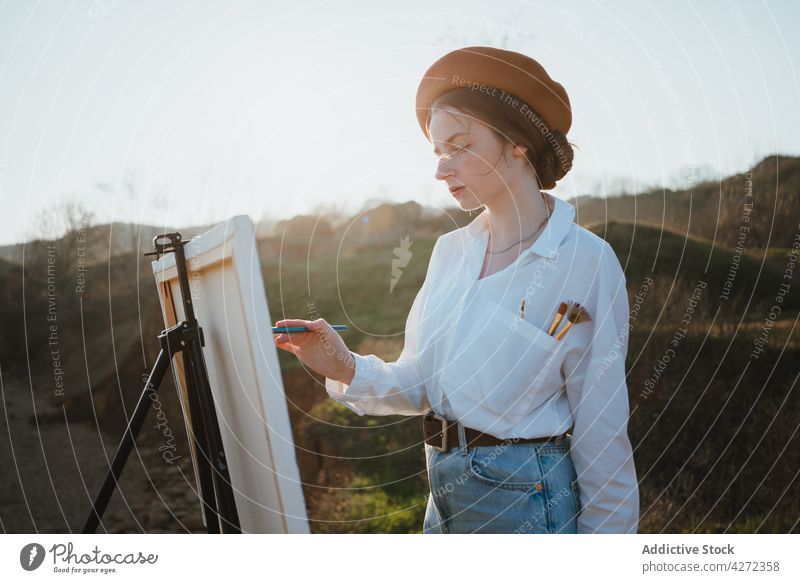Künstlerin am Ufer bei Sand und Meer beim Malen Frau Farbe zeichnen Hobby MEER Kunst Leinwand jung Staffelei Baskenmütze kreativ Kunstwerk Stil weißes Hemd