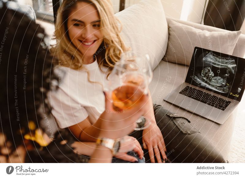 Ein fröhliches lesbisches Paar stößt mit Gläsern an und feiert die Schwangerschaft feiern Klirren Ultraschall Laptop Zahnfarbenes Lächeln romantisch Glück
