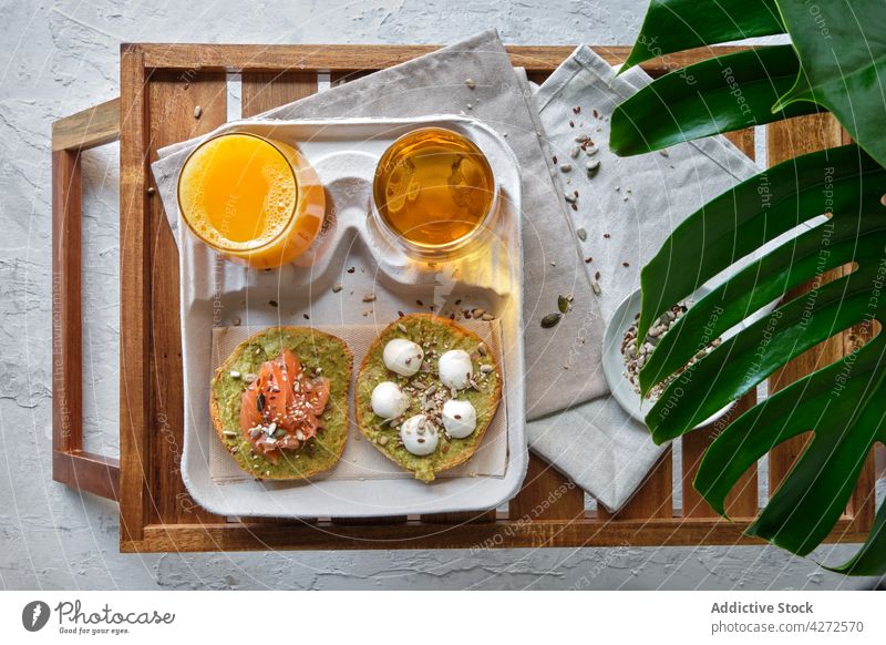 Gesundes Frühstück mit Avocado-Toasts und Getränken, serviert auf dem Tisch im tropischen Resort Zuprosten Lachs Saft Tee appetitlich gesunde Ernährung Burrata