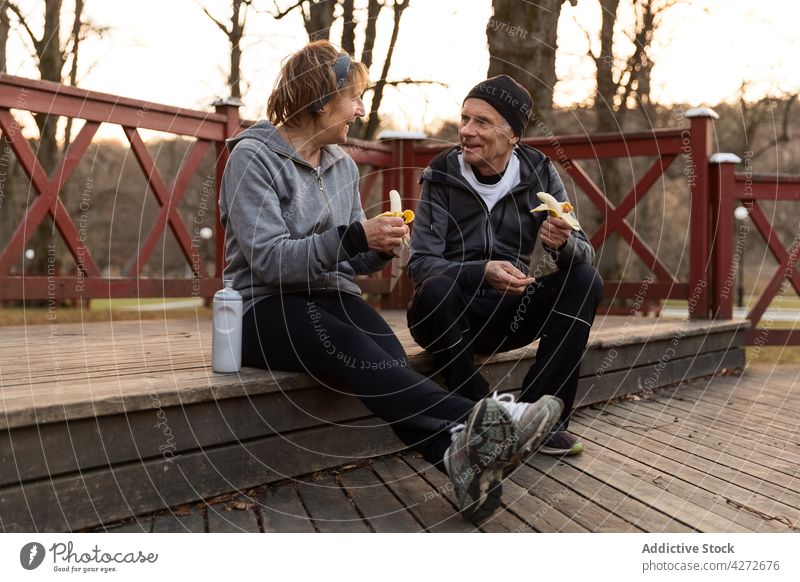 Positiv gestimmtes Paar isst Bananen nach dem Training Senior essen ruhen reden Pause Wellness Lebensmittel positiv Mann Frau gealtert Zusammensein älter