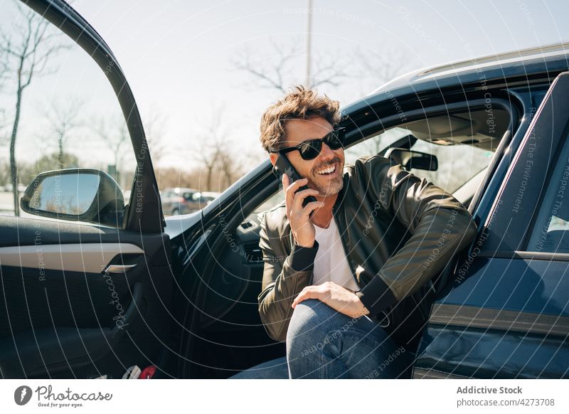 Gut gelaunter Mann, der im Auto mit seinem Smartphone spricht sprechen Nachricht Glück PKW Stadt benutzend Apparatur Gerät maskulin reden Funktelefon Gespräch