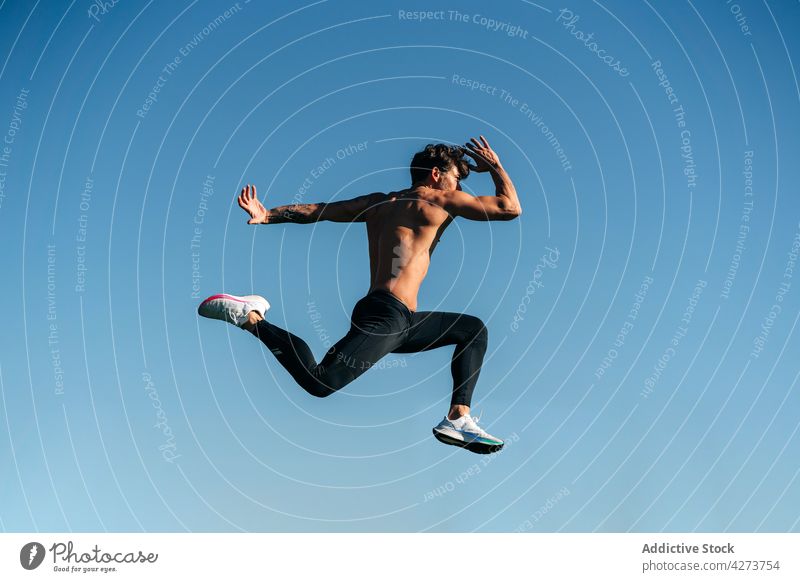 Schneller Läufer springt beim Training unter blauem Himmel laufen springen Sport Energie Geschwindigkeit schnell dynamisch ohne Hemd nackter Torso Mann
