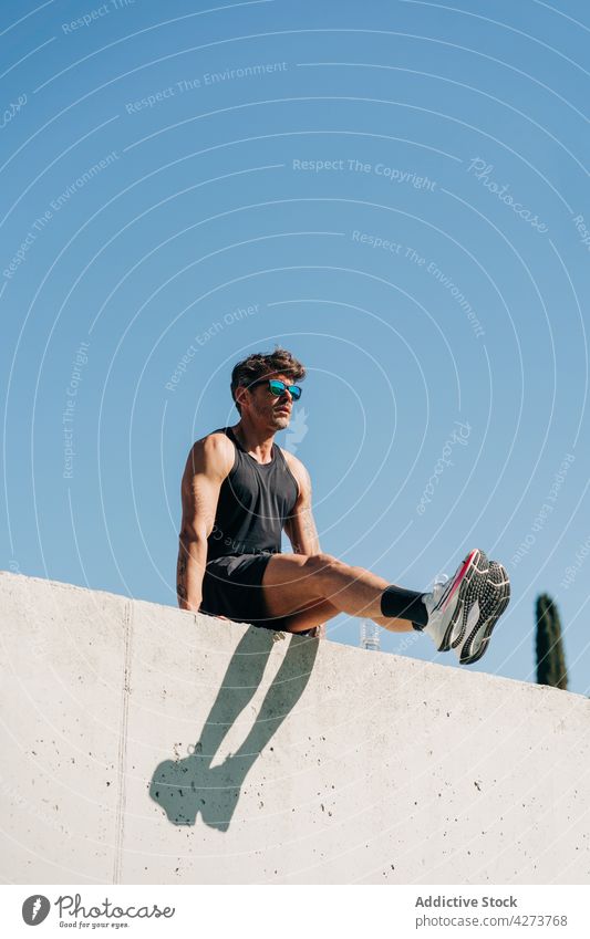 Sportler trainiert am Zaun unter blauem Himmel Training Übung stark Bizeps maskulin Blauer Himmel Mann wolkenlos Turnschuh Schatten Stärke Athlet üben