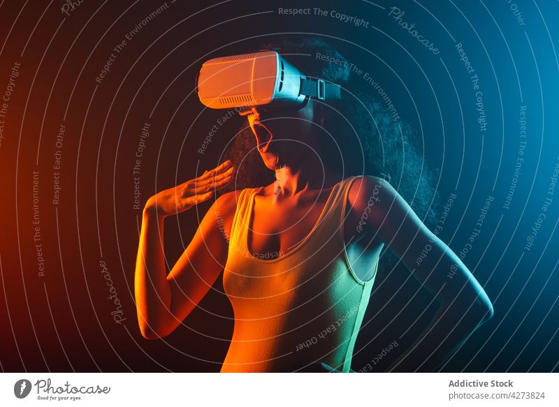 Unerkennbar verblüffte schwarze Frau erlebt virtuelle Realität in einer Schutzbrille VR erstaunt neonfarbig unterhalten eintauchen Technik & Technologie