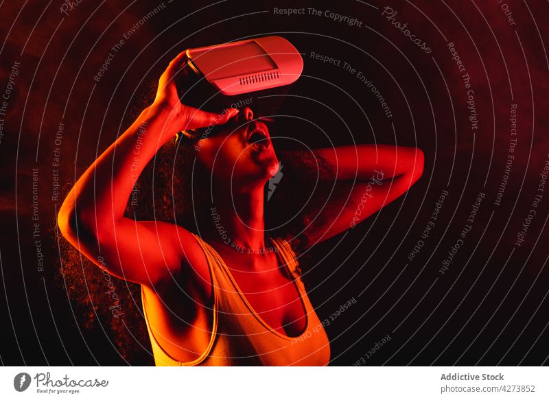 Unerkennbar verblüffte schwarze Frau erlebt virtuelle Realität in einer Schutzbrille VR erstaunt neonfarbig unterhalten eintauchen Technik & Technologie