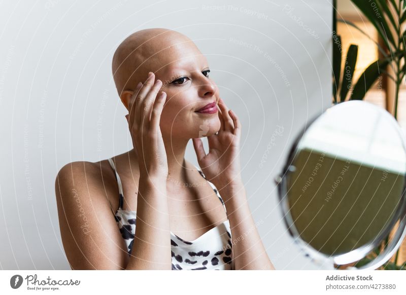 Selbstbewusste junge Frau mit Glatze lächelt und schaut in den Spiegel Lächeln Alopezie Krankheit kahl Stil selbstbewusst Tastkopf positiv haarlos rote Lippen