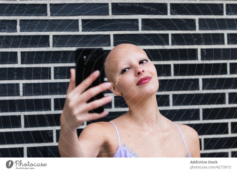 Fröhliche junge glatzköpfige Millennials, die lächelnd ein Selfie mit ihrem Smartphone machen Frau kahl Alopezie Krankheit Optimist heiter selbstbewusst