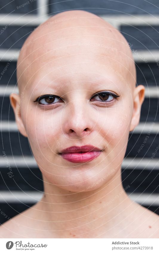 Haarlose Frau mit Make-up schaut auf der Straße in die Kamera kahl Alopezie Model Krankheit Persönlichkeit Vorschein selbstbewusst Porträt Windstille perfekt