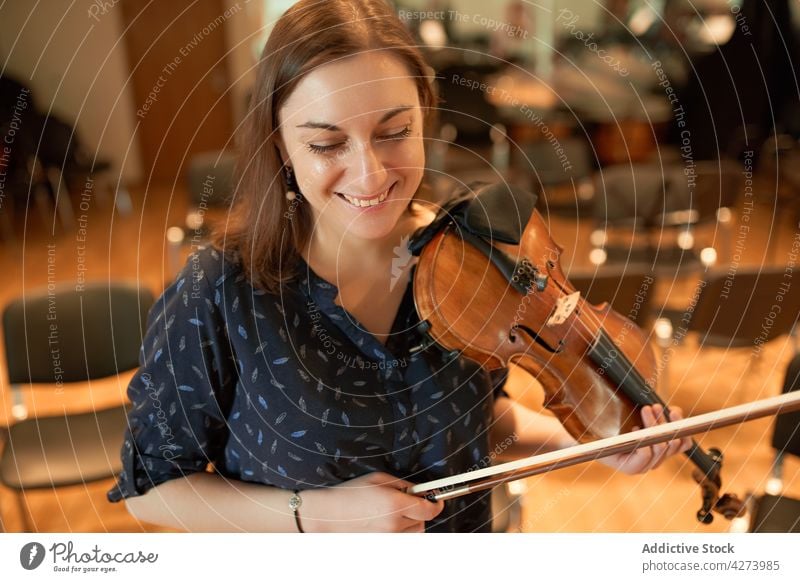 Glückliche Geigerin, die in einem Saal klassische Musik spielt Frau Musiker spielen Lächeln Freude ausführen Probe Instrument Fähigkeit Zahnfarbenes Lächeln