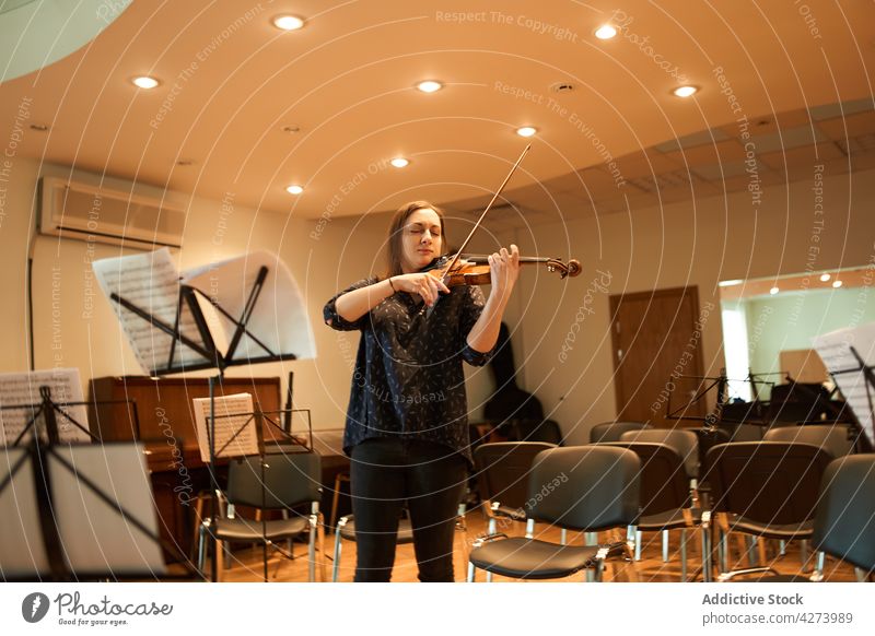 Eine Geigerin spielt klassische Musik in einem Saal Frau Musiker spielen ausführen Probe Instrument Fähigkeit Melodie Klang Augen geschlossen Talent genießen