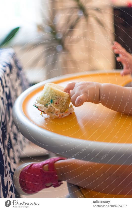 Erster Geburtstag/erste Torte: Einjähriges Baby greift nach umgestürzter Torte auf dem Hochstuhl ein Jahr alt erster Geburtstag einschlagen Cupcake Kuchen