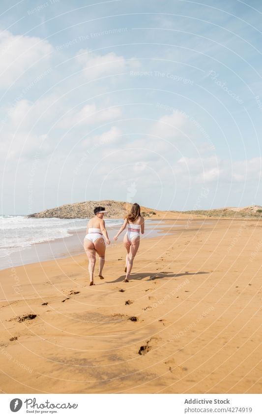 Damen laufen im Meer in der Nähe der Sandküste Frauen Freund Glück Spaß haben Strand Badeanzug Blauer Himmel Küste Meeresufer Sommerzeit sorgenfrei jung