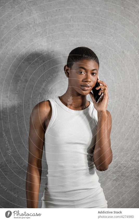 Stilvolles schwarzes Modell im Gespräch mit Smartphone auf grauem Hintergrund sprechen Individualität feminin Telefonanruf Frau benutzend Apparatur Gerät