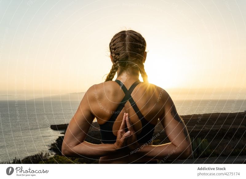 Unbekannte Frau mit betenden Händen hinter dem Rücken gegen das Meer Namaste Hand hinter dem Rücken Yoga üben Dehnung Gruß Wellness MEER Sonnenschein