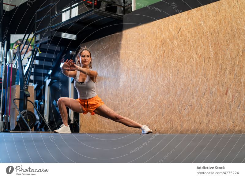 Fitte Frau streckt die Beine beim Training im Fitnessstudio Athlet Seitenlonge Dehnung Übung Aktivität üben Sportlerin passen Sportbekleidung physisch Aktion