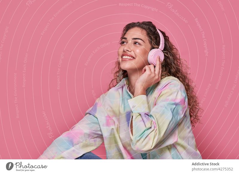 Lächelnde Frau, die mit Kopfhörern Musik hört zuhören benutzend Freizeit Wiedergabeliste Glück Teenager genießen heiter Gesang farbenfroh Gerät Optimist