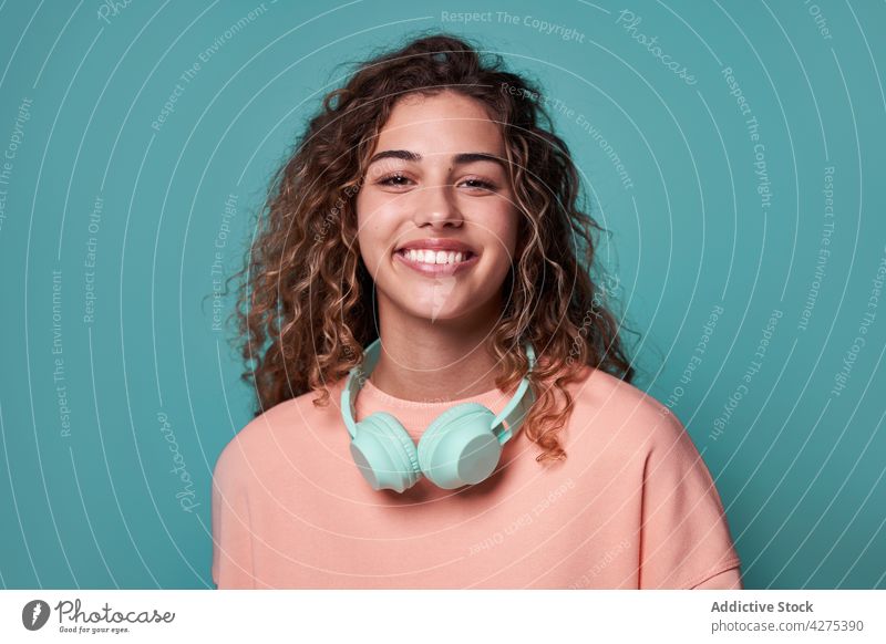 Lächelnde Frau mit Kopfhörern auf dem Hals im Studio charmant Persönlichkeit Apparatur lebhaft positiv Atelier Teenager cool Glück heiter Porträt hell jung froh