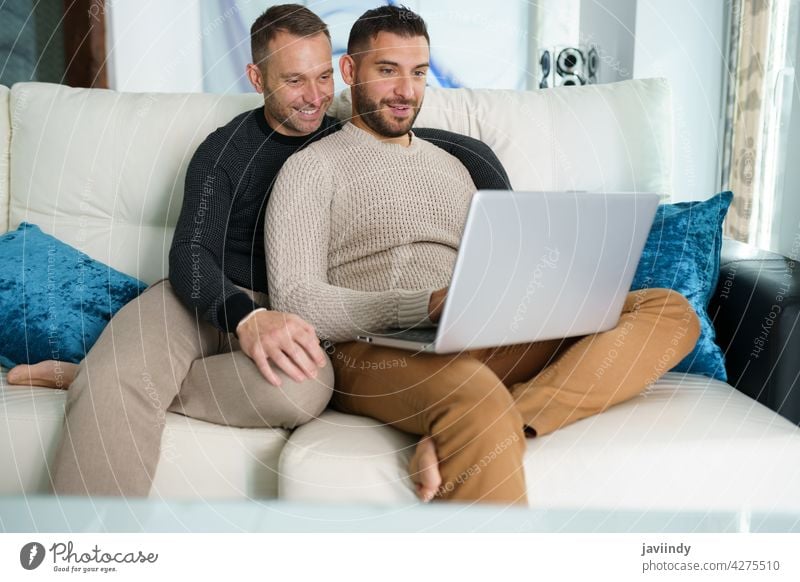 Schwules Paar, das seine Reisepläne gemeinsam mit einem Laptop berät. schwul Männer Homosexualität lgbt lgbtq männlich Partnerschaft Freund Menschen 30s