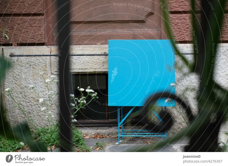 Blick durch Metallgartenzaun mit blauem Metalltisch zusammengeklappt an Hausfassade Zaun Garten Farbfoto Stadtleben Stadthaus Sandsteinfassade Außenaufnahme