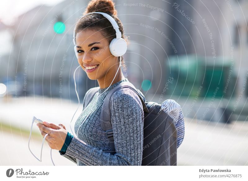 Glückliche junge Frau hört Musik in Kopfhörer in der Stadt im Freien Tag Positivität selbstbewusst sorgenfrei Menschen junger Erwachsener lässig schön attraktiv
