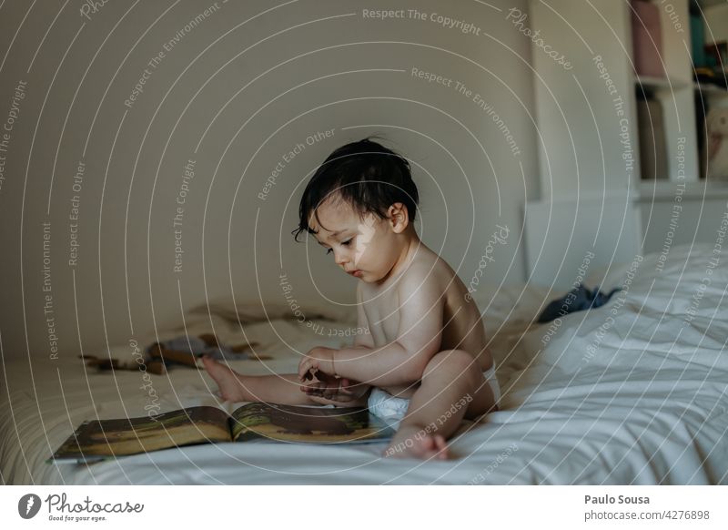 Kind lesend auf dem Bett Junge 1-3 Jahre Kaukasier zu Hause Schlafzimmer Lifestyle Buch authentisch heimwärts Kindheit Familie & Verwandtschaft niedlich