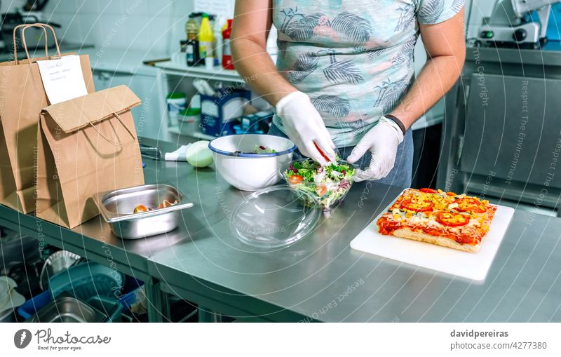 Unbekannter Koch bereitet Takeaway-Bestellungen vor unkenntlich Küchenchef Bestellungen vorbereiten Imbissbude Salatbeilage Großküche Paket Handschuhe Hygiene