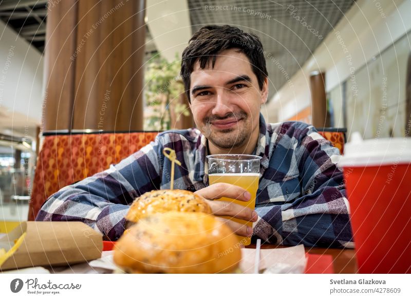 Mann isst Fastfood-Burger und trinkt Bier allein im offenen Bereich eines Restaurants in einem Einkaufszentrum Mahlzeit Lebensmittel Bar Glück Pub essen schnell