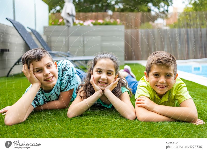 Porträt von drei Kindern auf einem Gras liegend Hintergrund schön Junge lässig Kaukasier heiter Kindheit genießen Familie Feld Freunde Freundschaft Spaß Mädchen