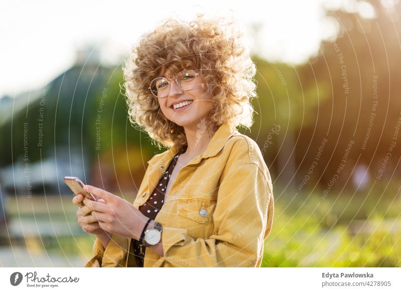 Junge Frau mit Mobiltelefon in der Stadt Jahrtausende urban Straße Großstadt stylisch Menschen junger Erwachsener lässig attraktiv Lächeln Glück Kaukasier