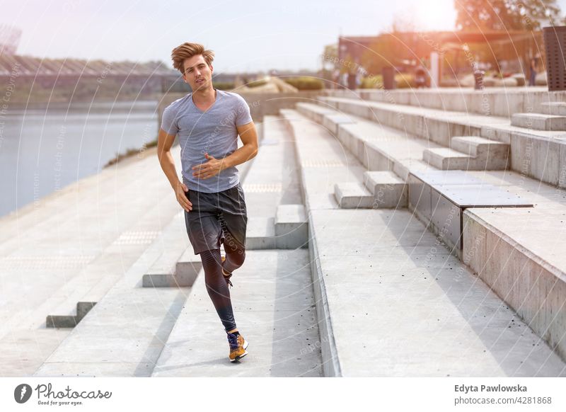 Junger Mann läuft in städtischem Gebiet Jogger Läufer Joggen rennen Menschen jung männlich Energie Übung Bekleidung trainiert. Fitness Erholung Sport