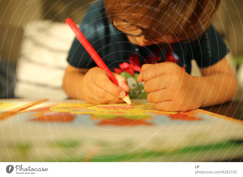Kind trägt Brille und schreibt, während es sehr konzentriert ist Oberkörper Porträt Muster talentiert zeichnen Zeichenutensilien Abenteuer Lebensfreude Freude