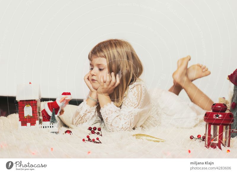 Kleines Mädchen auf dem Boden liegend, spielen mit Weihnachtsdekoration; Weihnachten Hintergrund mit Kopie Raum Kasten Postkarte Teppich Kaukasier Feier Kind