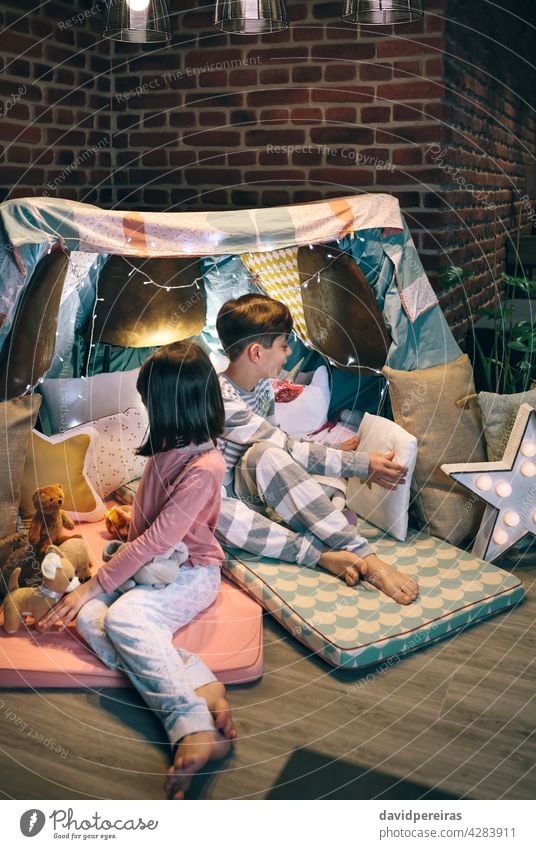 Kinder bereiten Zelt mit Stühlen und Bettlaken vor vorbereitend Tipi Bettwäsche Pyjama-Party Dekoration & Verzierung Platzierung Kissen Plüschpuppen heimwärts