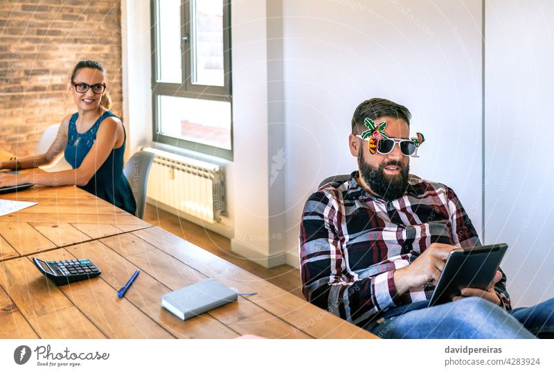 Geschäftsfrau schaut ihren Kollegen an, der eine komische Brille trägt, weil er in den Urlaub fährt Büro Arbeiter lustig Sommer Sonnenbrille letzter Tag Blick