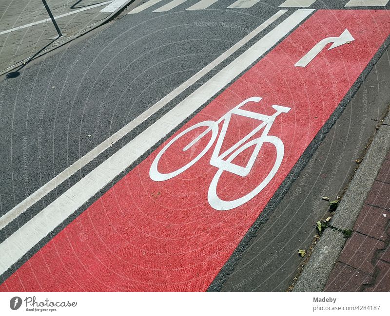 Neu angelegter roter Radweg mit Pfeil für Rechtsabbieger auf grauem Asphalt mit Zebrastreifen im Westend von Frankfurt am Main in Hessen Radfahrer Fahrrad