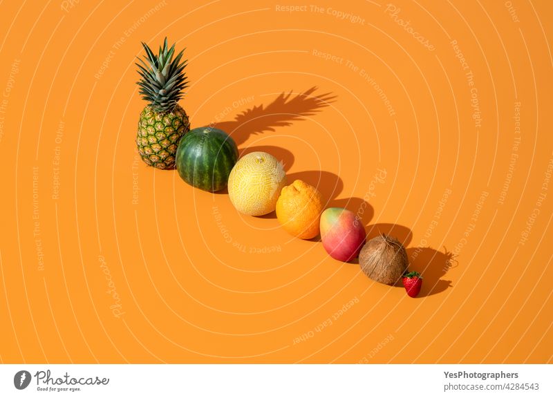 Sommerfrüchte in hellem Licht ausgerichtet auf einem orangefarbenen Hintergrund. oben Ananas angeordnet Kantalupe Zitrusfrüchte Kokosnuss Farbe Textfreiraum